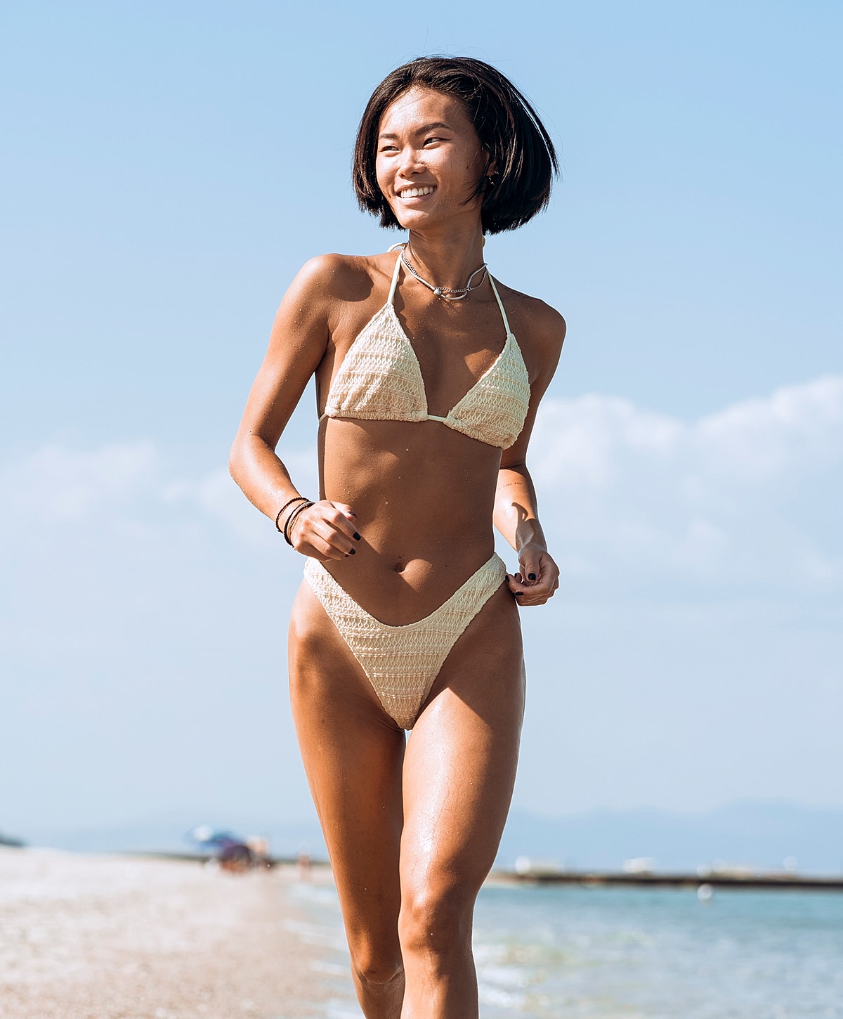 panniculectomy patient model running on beach in swimwear.