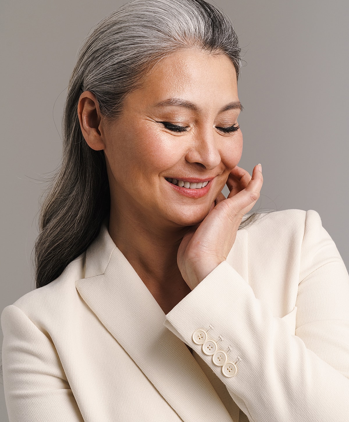 Smiling facelift patient model with gray hair in elegant attire.