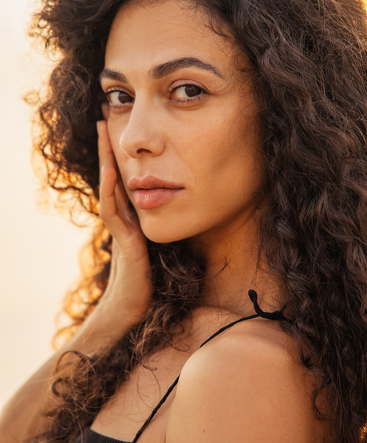 lip augmentation patient model with curly hair, natural light portrait.