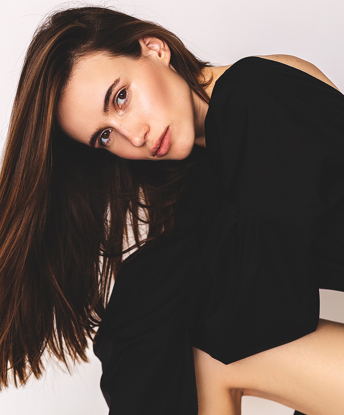 eyelid lift patient model in black attire with flowing hair.