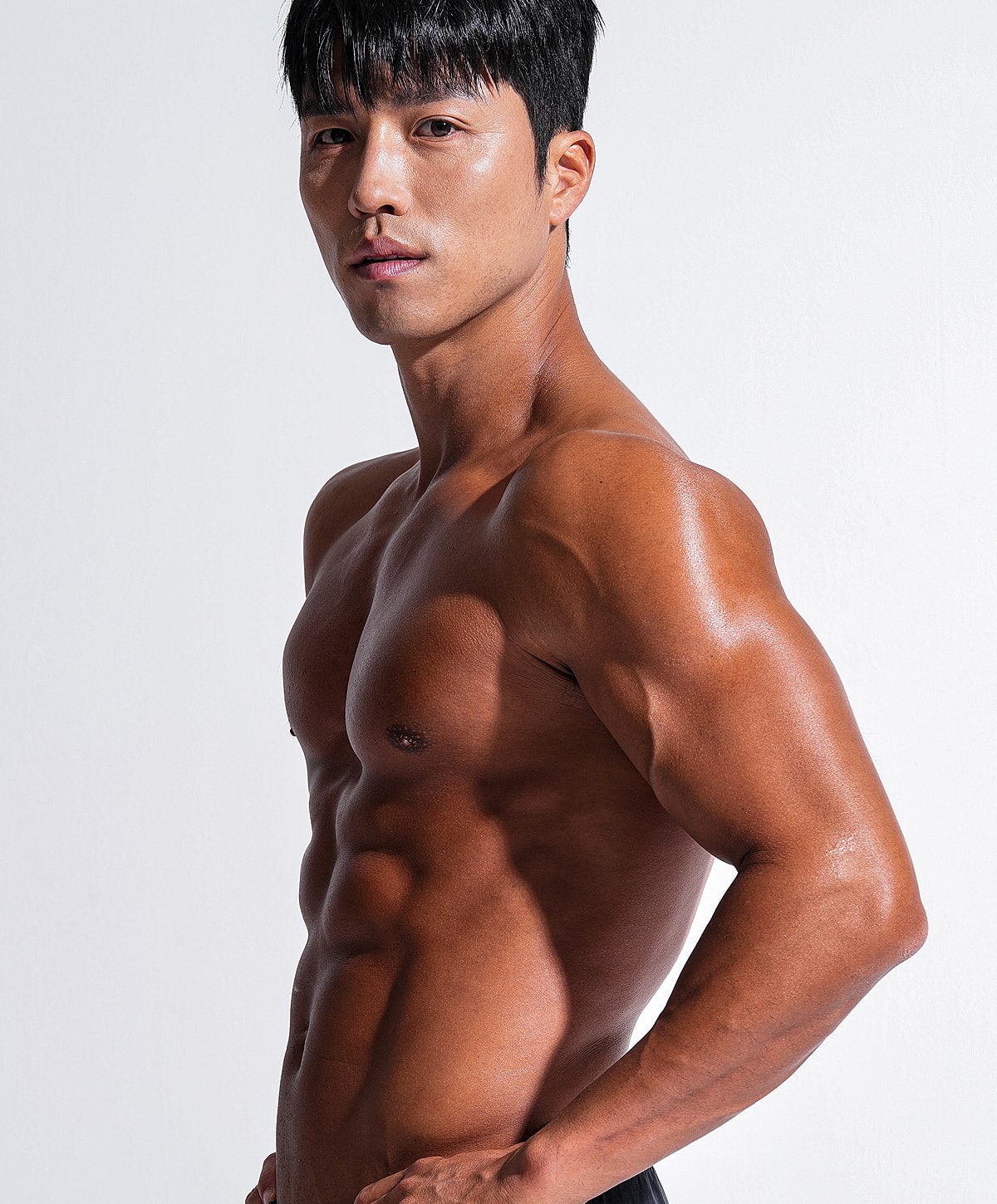 gynecomastia surgery patient model with athletic build posing against white background.