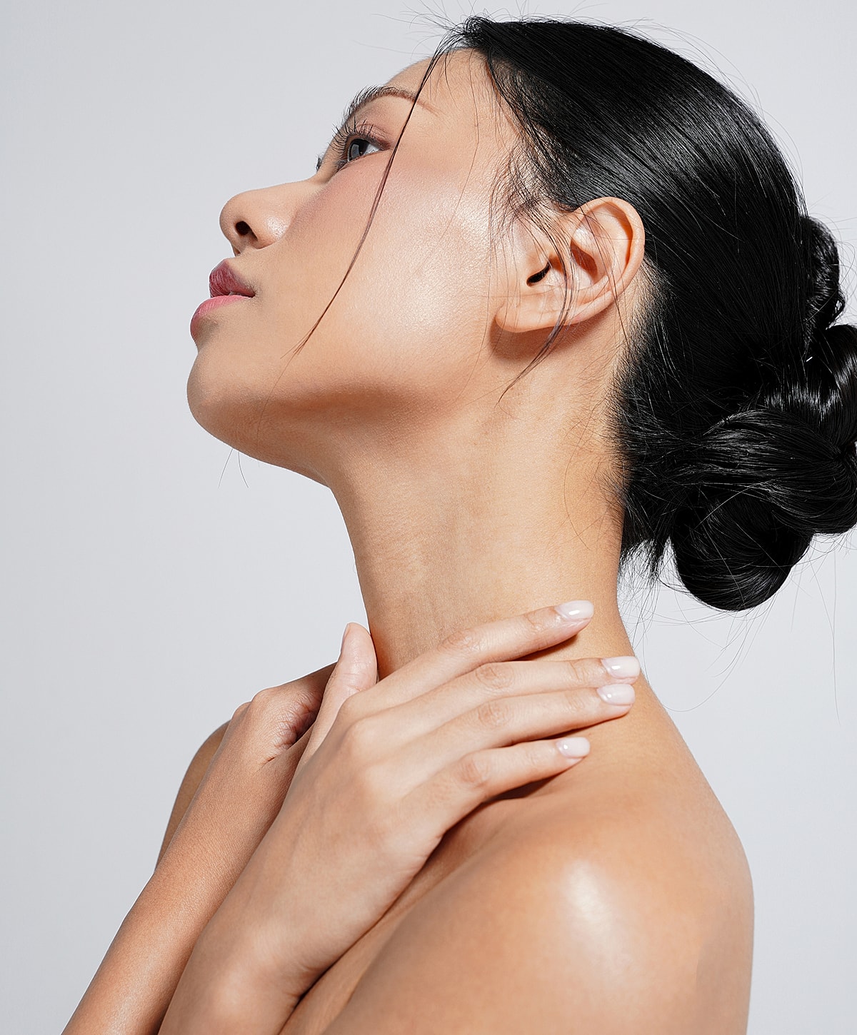otoplasty patient model with her hair in a bun touching her neck