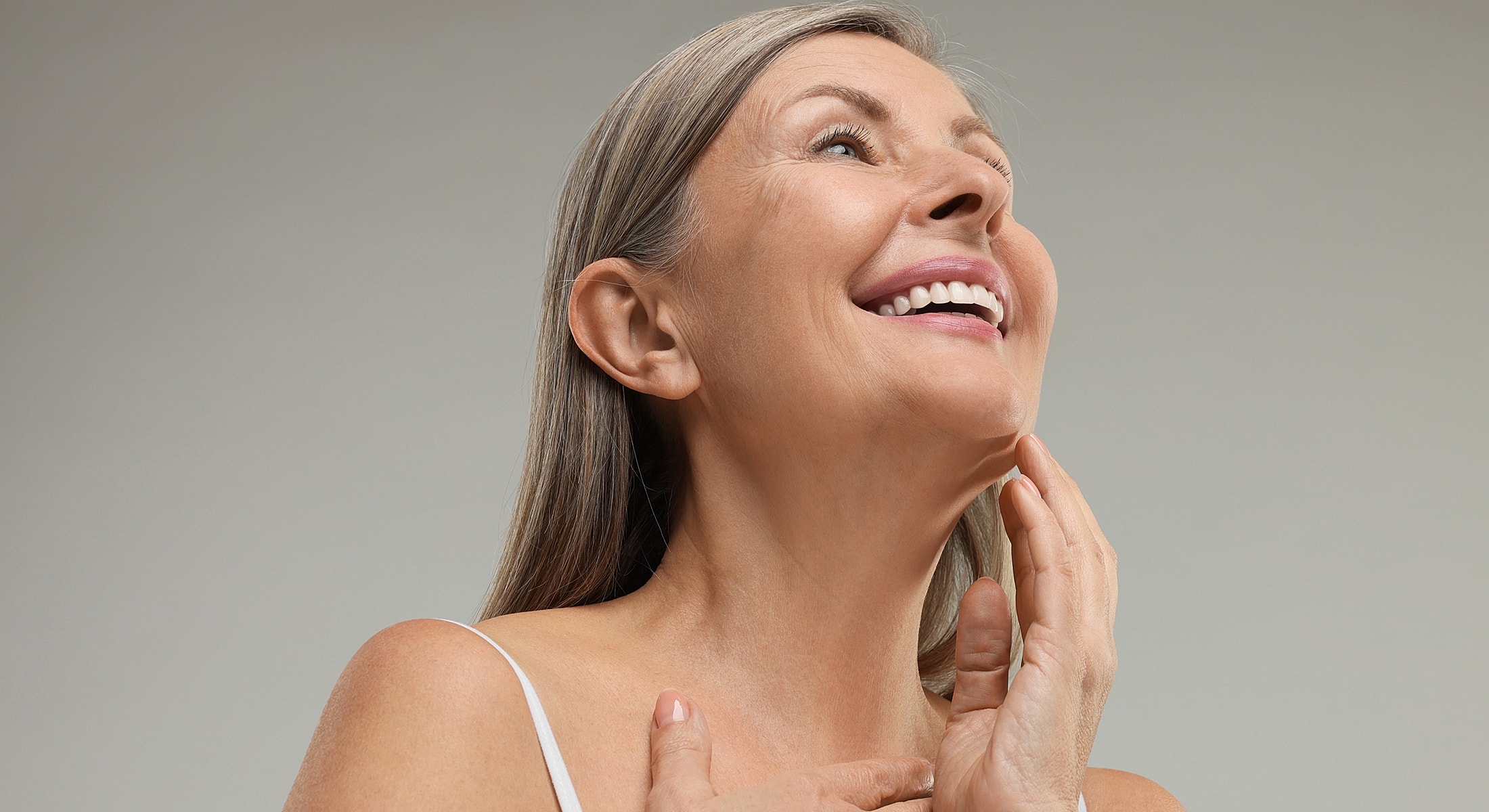 Smiling neck lift patient model with long hair touching chin.