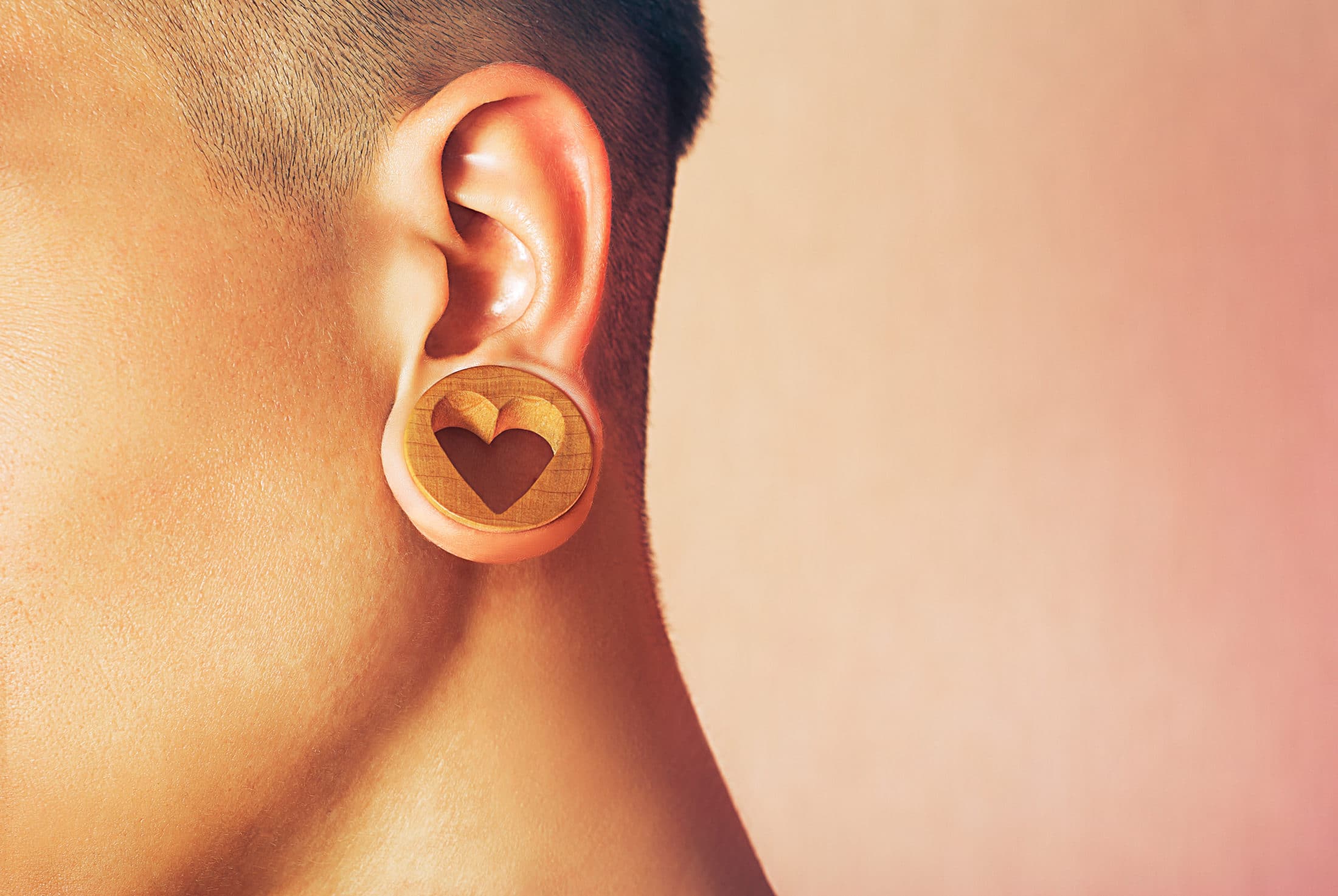 A piece of jewelry that fits into a stretched earlobe hole. Man with ear tunnel. Male ear with a ring