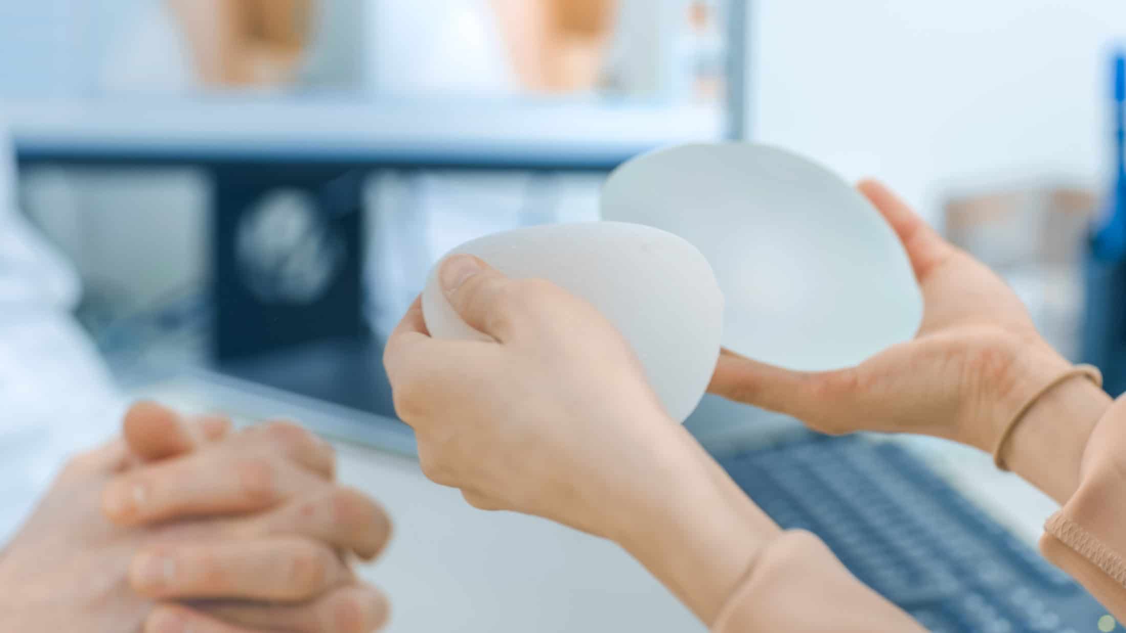 Plastic / Cosmetic Surgeon Shows Female Patient Breast Implant Samples for Her Future Surgery. Professional and Famous Surgeon Working in Respectable Clinic.